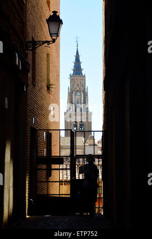 Silhouette di persona in vicolo stretto tra due edifici con la guglia della cattedrale di Toledo oltre Foto Stock