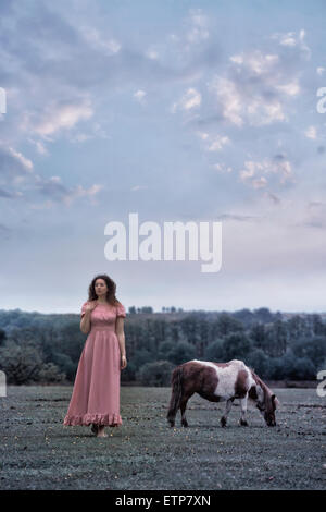 Una donna con un pony su un paddock Foto Stock