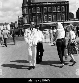 Una nuova mania - Voglia di abiti indossati dai pescatori a strascico a Lowestoft. Hylton Brighty, di anni 16, che indossa un abito bianco rifinito con nero, lui a guardare con interesse sono Maria Kampkin, 18, di Colindale (con velo) e Linda Suthers, di Kingsbury, che sono entrambi in vacanza in Suffolk. Il 19 luglio 1961. Foto Stock
