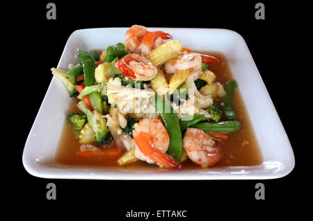 Stir fry di verdure miste e gamberetti nel piatto bianco isolato su sfondo nero Foto Stock