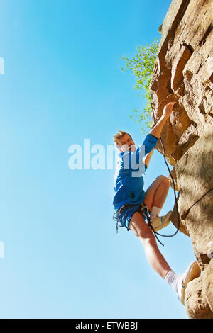 Giovane alpinista raggiungendo il top del rock Foto Stock