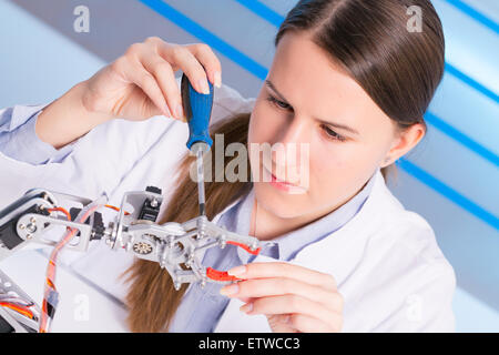 Schoolgirl regola il braccio di robot modello, ragazza in un laboratorio di robotica Foto Stock