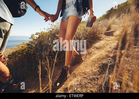 Close-up shot di una giovane coppia in un viaggio escursionistico. Immagine ritagliata del giovane uomo e donna escursionisti tenendo le mani mentre passeggiate sul Monte Foto Stock