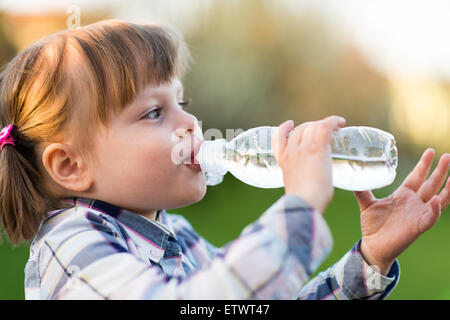 Ragazza di acqua potabile. Ritratto di carino bambina acqua potabile outdoor - molto leggera profondità di campo Foto Stock
