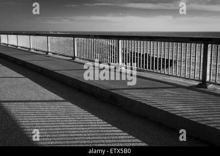 Nel tardo pomeriggio sole proietta ombre sul marciapiede di un ponte lungo la baia di San Francisco. Foto Stock