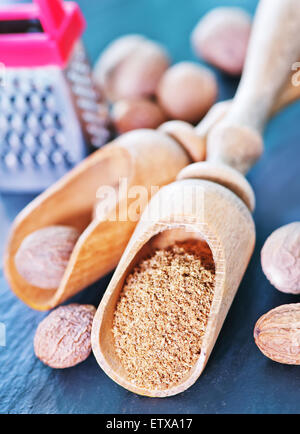 Noce moscata spice in cucchiaio di legno e su di una tavola Foto Stock