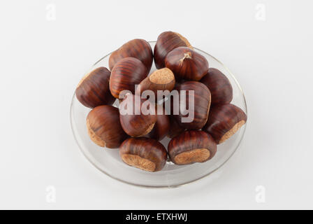 Pila di castagne su una piastra isolata su sfondo bianco Foto Stock