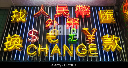 Luci al neon elencando varie monete al di sopra di cambio valuta Negozio di notte a Hong Kong Cina Foto Stock