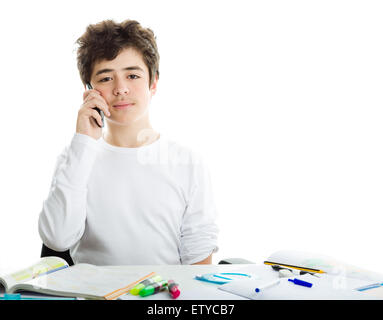 Bel ragazzo ispanica sta parlando al telefono cellulare mentre si fanno i compiti e indossando un bianco maniche lunghe t-shirt Foto Stock