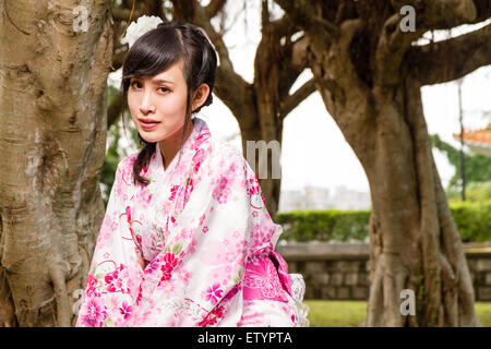 Donna asiatica in kimono da alberi in giardino Foto Stock