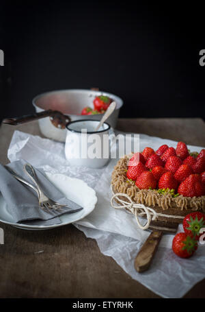 Crostata di fragole con nastro sul tavolo di legno con piatti Foto Stock