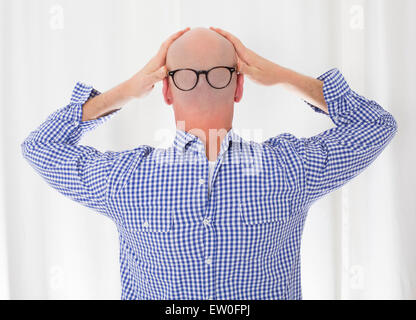 Retro di un calvo uomo in una maglietta blu in retromarcia con gli occhiali Foto Stock