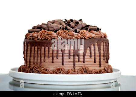 Torta al cioccolato con salsa al cioccolato spruzzata glassa e riccioli di cioccolato su sfondo bianco Foto Stock