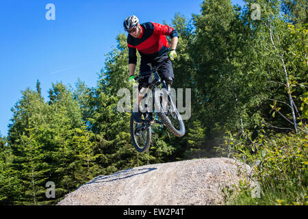 Mountain bike rider salta sopra una pista sterrata kicker Foto Stock