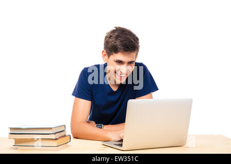 Sorridente studente maschio seduti a tavola e utilizzando computer portatile isolato su sfondo bianco Foto Stock