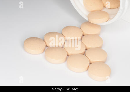 Tablet medications fuoriuscita da una bottiglia di plastica bianca. Foto Stock