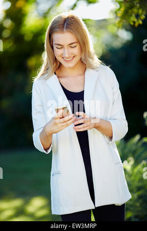 Lettura della ragazza messaggio sul suo iPhone Foto Stock