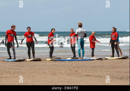 Lezioni di surf presso una scuola di surf sulla spiaggia di Polzeath Cornwall, Regno Unito Foto Stock