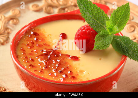 Creme brulee in un piatto rosso Foto Stock