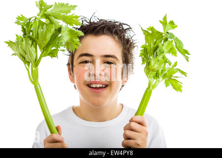 Bel ragazzo di ispanici in bianco a maniche lunghe t-shirt è sorridente tenendo sedano verde bastoni con entrambe le mani Foto Stock