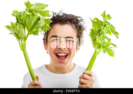 Bel ragazzo di ispanici in bianco a maniche lunghe t-shirt è sorridente tenendo sedano verde bastoni con entrambe le mani Foto Stock