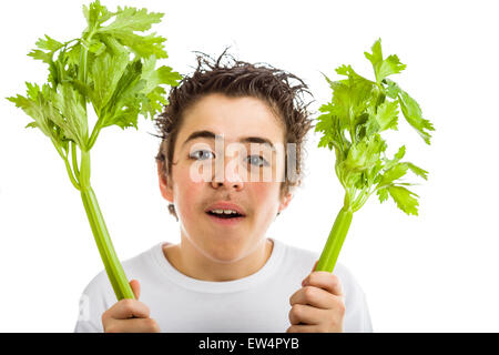 Bel ragazzo di ispanici in bianco a maniche lunghe t-shirt è sorridente tenendo sedano verde bastoni con entrambe le mani Foto Stock