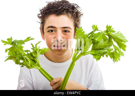 Bel ragazzo di ispanici in bianco a maniche lunghe t-shirt è sorridente tenendo sedano verde bastoni con entrambe le mani Foto Stock