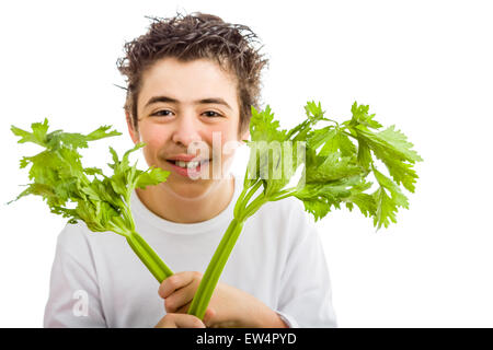 Bel ragazzo di ispanici in bianco a maniche lunghe t-shirt è sorridente tenendo sedano verde bastoni con entrambe le mani Foto Stock