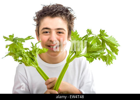 Bel ragazzo ispanica con morbido in pelle bianca con maniche lunghe t-shirt è sorridente tenendo sedano verde bastoni con entrambe le mani Foto Stock