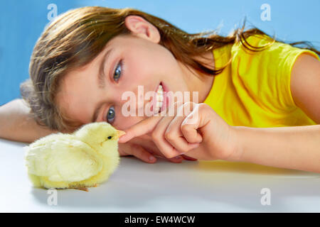 Kid ragazza con pulcino giallo giocando sulla tavola con sfondo blu Foto Stock