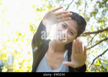 Giovane donna di raggiungere le mani e sorridendo alla telecamera Foto Stock