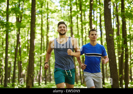Due amici che corre attraverso il bosco su un sentiero per jogging Foto Stock
