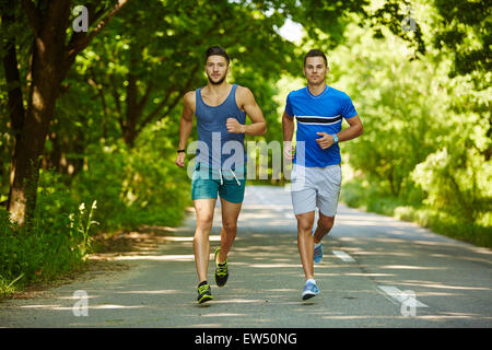 Due amici che corre attraverso il bosco su un sentiero per jogging Foto Stock