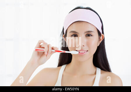 Giovane donna spazzolare i denti con il sorriso Foto Stock