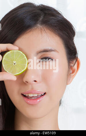 Giovane donna azienda fetta di limone e sorridente alla fotocamera Foto Stock