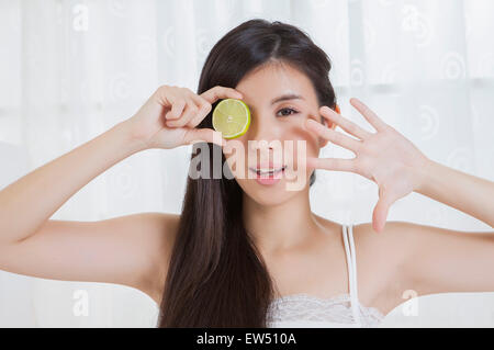 Giovane donna azienda fetta di limone e sorridente alla fotocamera Foto Stock
