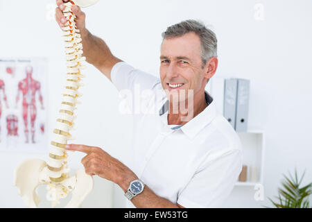 Medico sorridente che mostra la colonna vertebrale anatomica Foto Stock