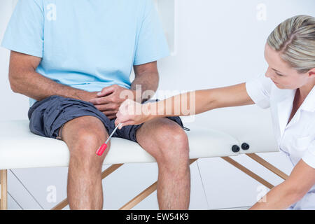 Controllo medico riflessi del ginocchio del paziente Foto Stock