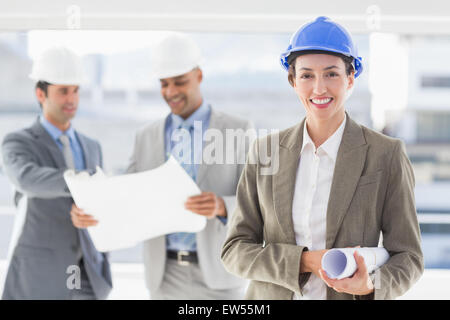 Uomini d affari e una donna con duro cappelli e blueprint di contenimento Foto Stock