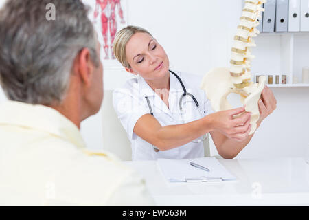 Medico mostrando il suo paziente un modello della colonna vertebrale Foto Stock