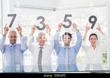 Sorridente team aziendale che mostra una carta con valore nominale Foto Stock