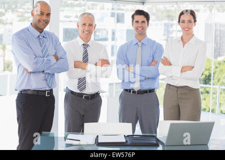 Il team di Business sorridente in telecamera con le braccia incrociate Foto Stock