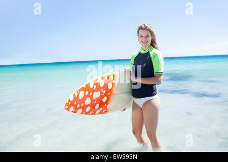 Montare donna bionda in piedi in acqua e tenendo la tavola da surf Foto Stock