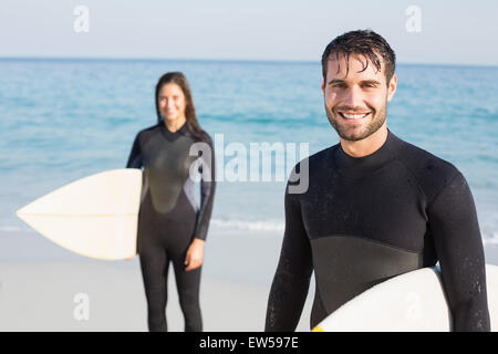 Coppia felice in neoprene con tavola da surf in una giornata di sole Foto Stock