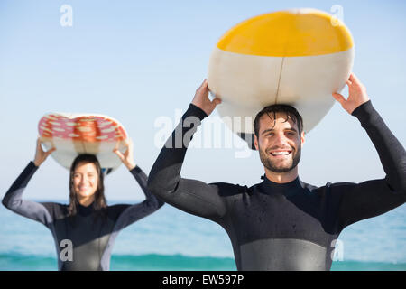 Coppia felice in neoprene con tavola da surf in una giornata di sole Foto Stock