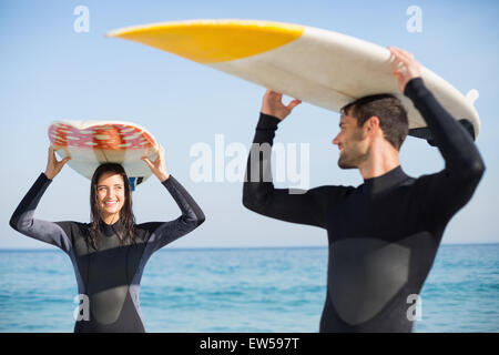 Coppia felice in neoprene con tavola da surf in una giornata di sole Foto Stock