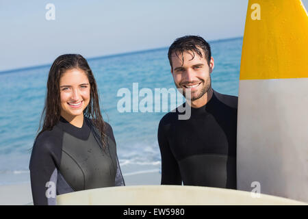 Coppia felice in neoprene con tavola da surf in una giornata di sole Foto Stock