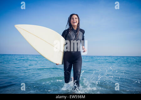 Donna in neoprene con una tavola da surf in una giornata di sole Foto Stock