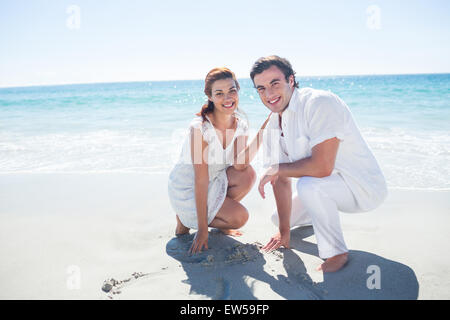 Coppia felice disegno forma di cuore nella sabbia Foto Stock