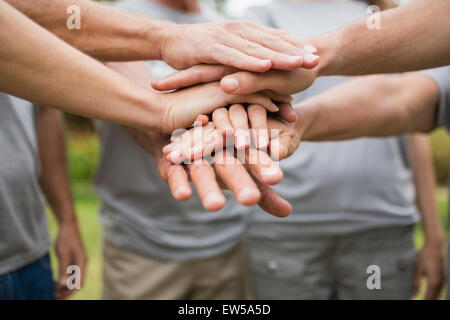 Felice famiglia di volontariato di mettere le loro mani insieme Foto Stock